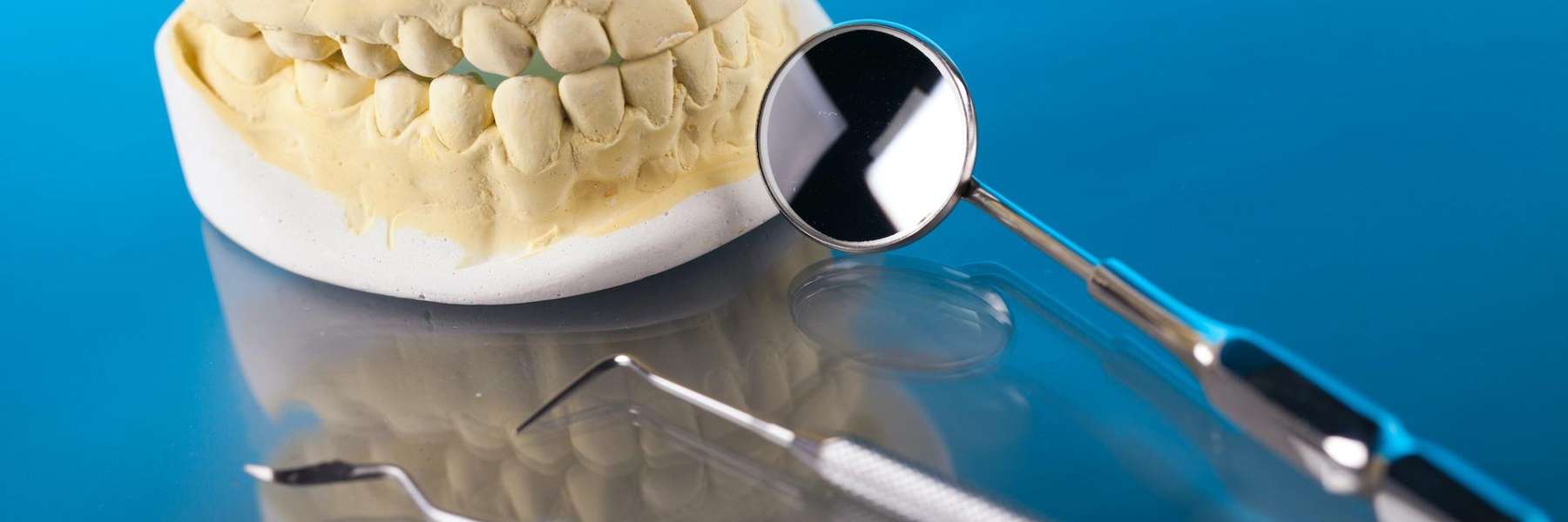 Molded teeth with mouth mirror and scalers on a table in South Carolina